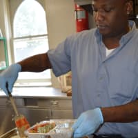 <p>Shawn McKie of Prospect Park, an employee of Valley Hospital, puts eggplant parmigiana in meal trays that will go to the homes of people who can&#x27;t cook or shop for themselves.</p>