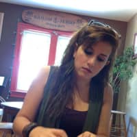 <p>Christina &quot;Alexa&quot; Houlis looks through her songbook, where she writes all of her original music, at Cool Beans, in Oradell.</p>