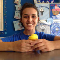 <p>Clifton staff member, Marissa Rossi, with her favorite cupcake, the Lemon Drop: yellow cake filled with lemon pie filling and topped with cream cheese icing.</p>