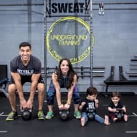<p>Moshe and Renee Klyman practice kettle bell swings with their two sons.</p>