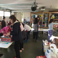 <p>Northvale Girl Scouts work under the cover of a garage to prepare gifts for those in need. </p>