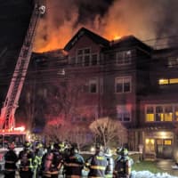 <p>Flames shoot through the roof of the burning condo on Richards Avenue in Norwalk on Monday evening.</p>