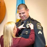 <p>Kim Arnette pins a new badge Weston Police Sgt. Travis Arnette.</p>
