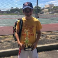 <p>A player stands with a trophy he won in a USTA tennis tournament hosted by Slammer Tennis World in Norwalk.</p>