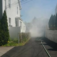 <p>Greenwich firefighters destroy part of a fence at a home on Valley Road after it caught fire.</p>