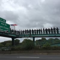 <p>Fellow firefighters of Michael Fahy, who was killed on Tuesday, line the overpass as his body is taken to the funeral home.</p>