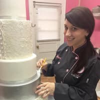 <p>Arlene Murray of Lyndhurst puts the finishing touches on a wedding cake.</p>