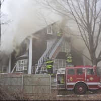 <p>Firefighters battle the smoky blaze at the Norwalk home on Saturday.</p>