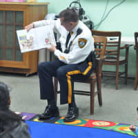 <p>East Rutherford Police Chief Larry Minda reads to children at the library.</p>