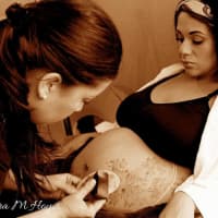 <p>Laura Hoyos of Englewood, who owns Paint 2 Smile, works on a belly-painting client.</p>