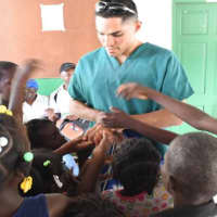 <p>Vittorio Mena greets children at a clinic in Haiti in August of 2014.</p>