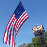 <p>Teaneck and Ridgefield Park fire departments raise the colors as the last WTC beam is transported from NYC.</p>