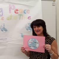 <p>Esther Fletcher with a poster her students made for the Peace By Piece project.</p>