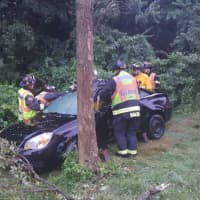 <p>Westport firefighters respond to a crash scene after a car went down an embankment on the Merritt Parkway during heavy rains on Saturday morning.</p>