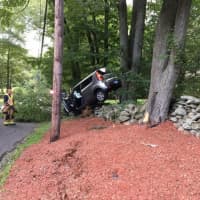 <p>The Huntington Fire Co. responds to the crash of an SUV that ended up balanced on a stone wall on Thompson Street in Shelton on Thursday.</p>