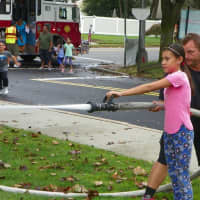 <p>A New Milford girl operates a fire hose with assistance from a firefighter.</p>