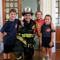 <p>Hackensack Leitenant Mike Oates with his children, who attend the Fairmount School. Firefighters on Monday visited Fairmount, where they made a presentation and let the students try on their bunker gear.</p>