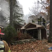 <p>Fairfield firefighters perform ventilation operations at a house fire on Saw Mill Road in Weston on Saturday.</p>