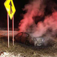 <p>A car smolders after it burst into flames on Route 25 in Trumbull at 3 a.m. Monday.</p>