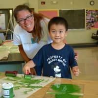<p>DAC Visual Arts Director Beth Cherico assists a young student with a printmaking project in the DAC Visual Arts Studio.</p>