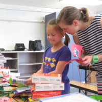 <p>Second grader Sophie Kwun gets some help organizing the donations from her mom, Susan</p>