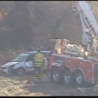 <p>A crew on a wrecker works to remove a car that rolled down an embankment off Exit 7 eastbound in Danbury on Wednesday morning.</p>