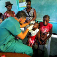 <p>Vittorio Mena examines the eyes of a young girl during a August 2014 humanitarian trip to Haiti.</p>