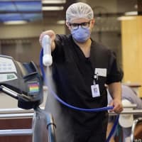 <p>A Holy Name Health nurse sprays down a treadmill</p>
