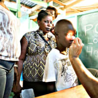 <p>Vittorio Mena checks the eyes of a boy during a humanitarian trip to Haiti in August of 2014.</p>
