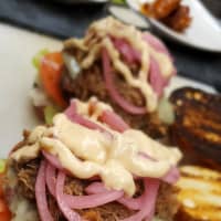 <p>Hair of the Dog&#x27;s &quot;All Hellz Breakin&#x27; Loose&quot; burger, an eight ounce patty topped with maple bourbon braised pork, bacon, pickled red onion, sharp cheddar, smoky remoulade, lettuce and tomato on a pretzel roll</p>