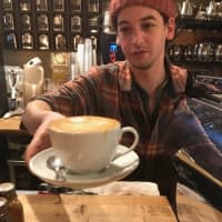 <p>A barista at Art Cafe of Nyack prepares to bring a brimming cup of coffee to a customer.</p>