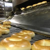 <p>Bagels glide past, hot out of the oven.</p>