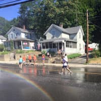 <p>The fire department&#x27;s hose sprays water, creating a rainbow, as runners trot past during Monday&#x27;s John DeMille Fiecracker Road Race in Bethel.</p>