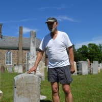 <p>Robert Neal Carpenter stands by a headstone he repaired at the Wyckoff Reformed Church Cemetery.</p>