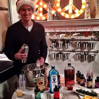 <p>Chris Halstead, husband of The Beehive owner Sandra Tobey Halstead, plays bartender during the 2014 Holiday Shop &amp; Stroll.</p>