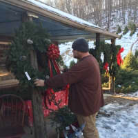 <p>PJ Madsen, an employee at the Cockburn Family Farm in Garrison, adjusts one of the many wreaths that he makes there on recent afternoon.</p>