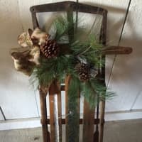 <p>Pretty greens and pinecones decorate an old sled at Cockburn Family Farm in Garrison.</p>