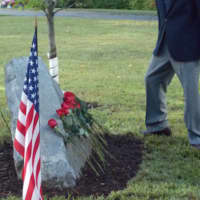 <p>Darien veteran Charles Scribner places a rose at the base of the 9/11 Memorial behind Middlesex Middle School.</p>