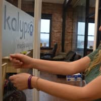 <p>Kalypso Media&#x27;s Theresa Merino puts the company sign on her new office door in Ridgewood&#x27;s Lincoln Building.</p>