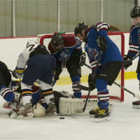 <p>RTH (in blue) tries to clear a loose puck in front of its net.</p>