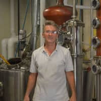 <p>Robert Schulten with some of the equipment used to make corn whiskey, gin and vodka at Asylum Distillery in Bridgeport.</p>