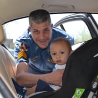<p>Paramus Police Sergeant Brian Linden fits Lucas into his brand new donated car seat from Buy Buy Baby.</p>