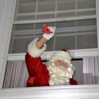 <p>Santa Claus pops out of a window at Mount Kisco Village Hall.</p>