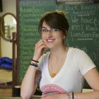 <p>Redding Roasters Owner Kaitlyn Heisler, in front of a chalkboard filled with coffee choices.</p>