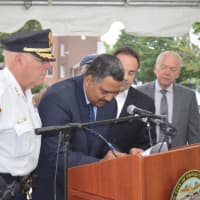 <p>James Slaughter, interim executive director of the Bridgeport Housing Authority, signs a memorandum of understanding as Police Chief AJ Perez, left, and Mayor Joe Ganim, right, look on.</p>