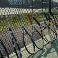 <p>Tennis rackets lined up along a fence for the John Jay tennis courts.</p>