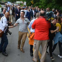 <p>A member of Hillary Clinton&#x27;s entourage (center, in grey shirt) motions a press scrum to move back as New Castle&#x27;s Memorial Day parade gets underway.</p>