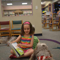 <p>Megan Corcoran, 7, reads a book to Siena the Spinone Italiano at Stratford Public Library.</p>