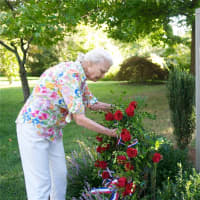 <p>Lynn Watson, of the Green Acres Garden Club, places a wreath at the 9/11 memorial.</p>