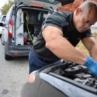 <p>Mechanic Roberto Gonzalez of Nomad Oil works on a car in Rutherford with the company van behind him. The van runs an air compressor to help with tools and, when necessary, a pneumatic lift.</p>
